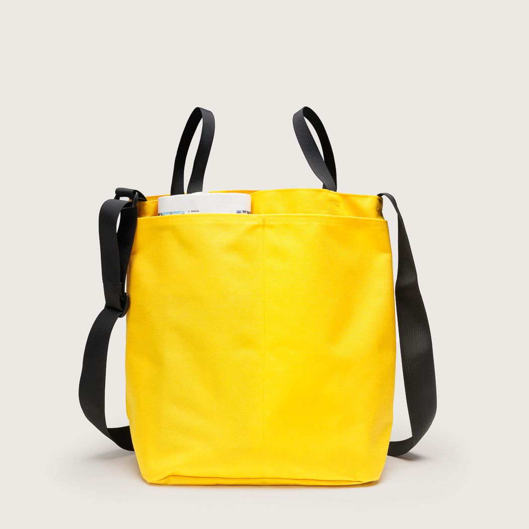 Two full length back pockets on yellow Mid Side Handle Tote with black handles and adjustable shoulder strap