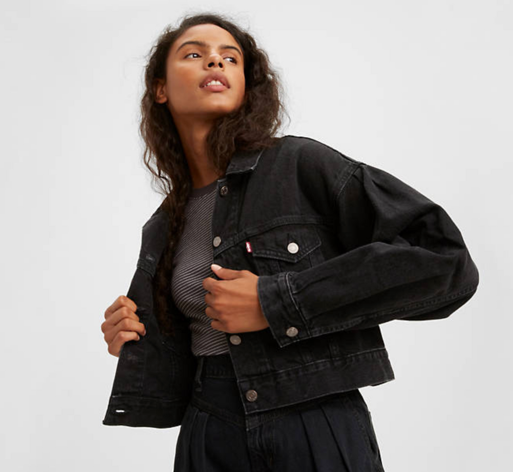 Model wearing black cropped jean jacket with front button flap pockets