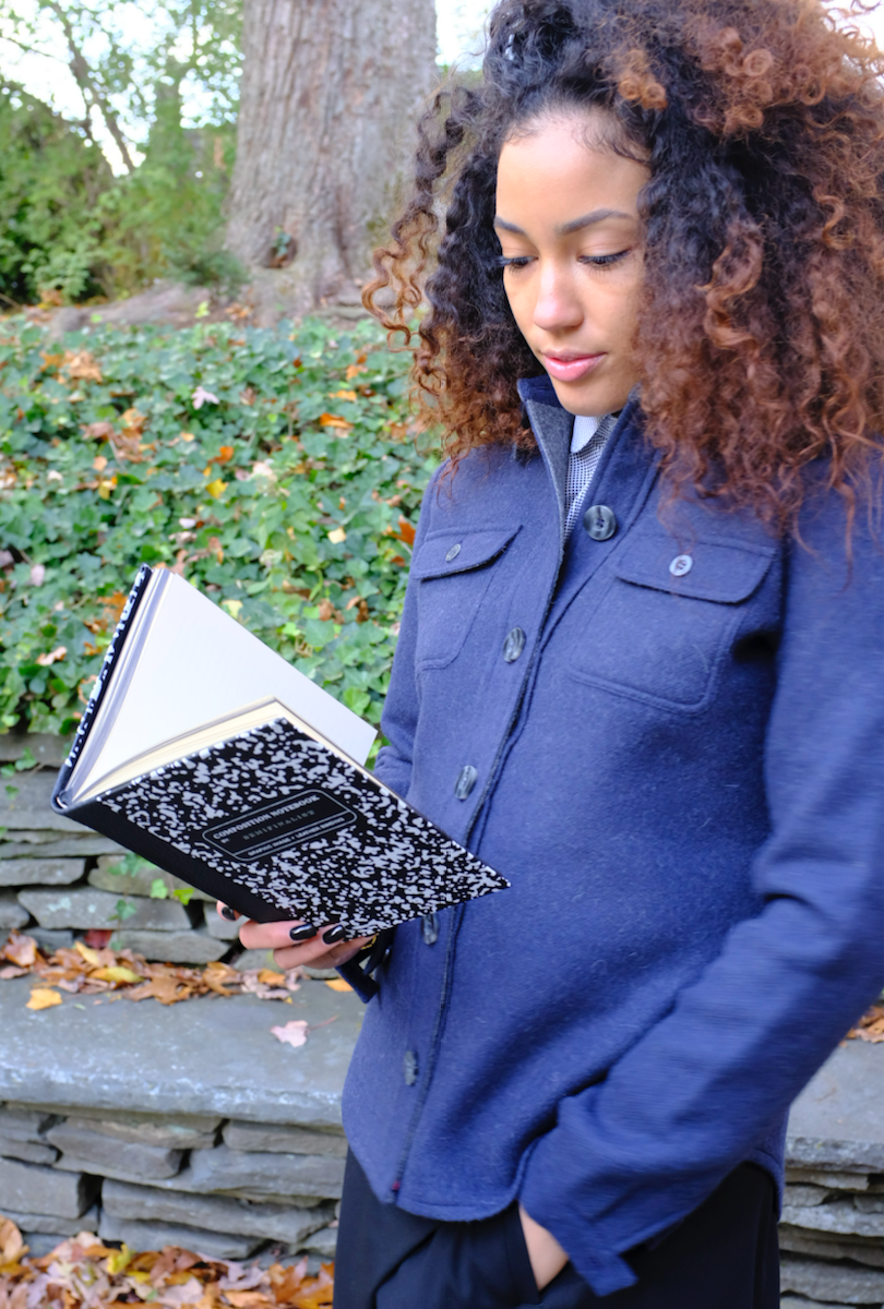 Female model holding an open black & white composition notebook