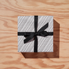 Black & white gift wrapped box reading "YOU'RE WELCOME" with black ribbon