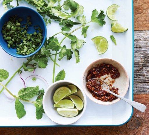 A platter of fresh cilantro, limes and pepper flakes used in Vietnamese cooking