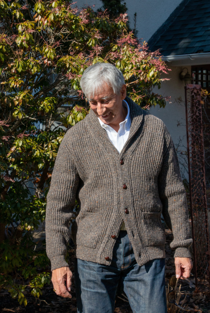 Model wearing brown/grey button-down sweater with 2 front pockets and shawl collar