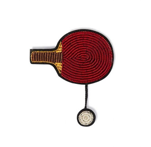Embroidered pin of a red ping pong paddle with a brown handle and a white ping pong ball