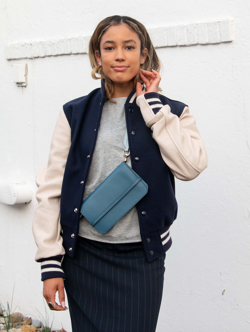 Female model wearing blue leather wallet clutch across her body