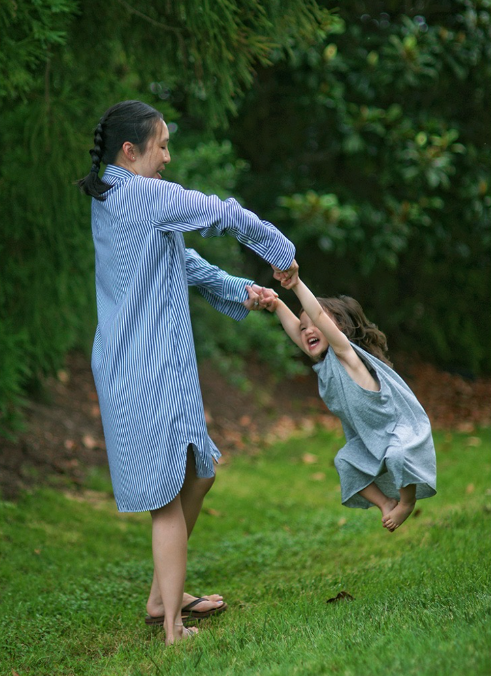 Female model wearing blue & white striped long sleeve shirtdress, playing with small child