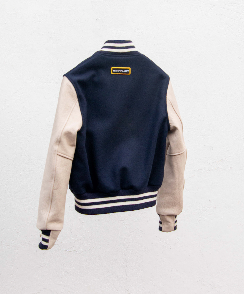 back view:  navy blue varsity jacket with white sleeves with Semifinalist logo patch