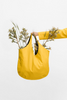 Hand held yellow u-shaped bag  with  wildflowers protruding from top opening