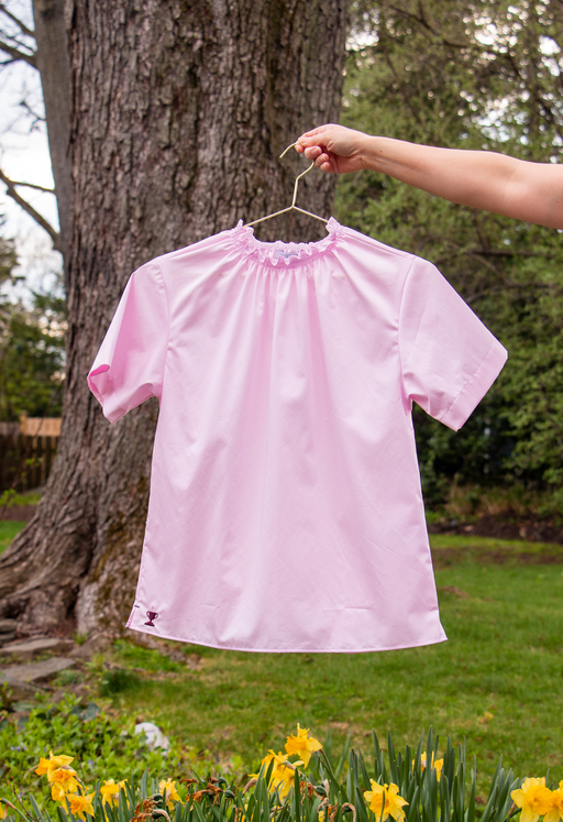 Short sleeve pink shirt with ruched neckline on hanger