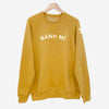 Mustard colored long sleeve sweatshirt with appliqué reading "BÁNH MI" on front
