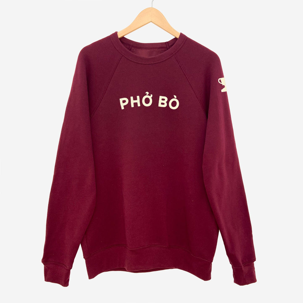 Burgundy long sleeve sweatshirt with appliqué reading "PHÓ BÒ" on front