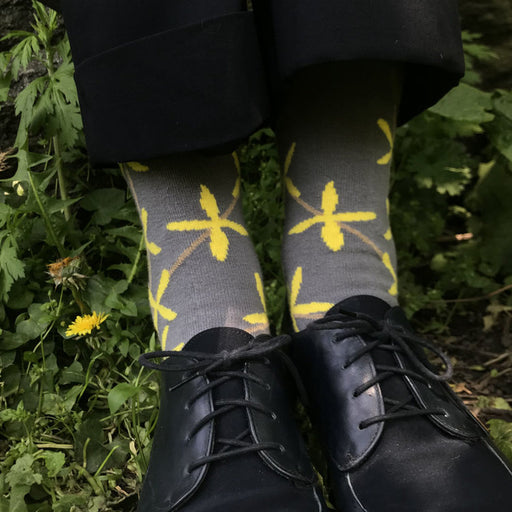 Model wearing grey women's sock with yellow forsythia design, and black shoes