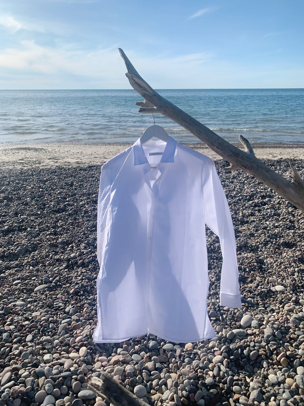 White button down long sleeve collar shirt on a hanger at the beach