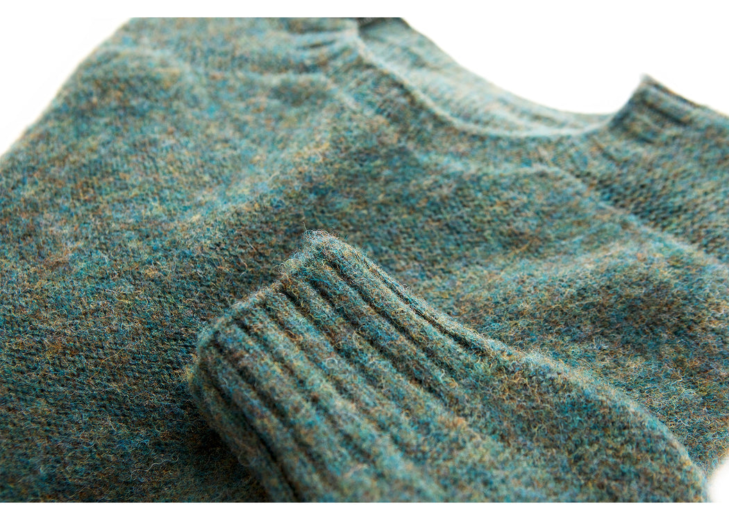 Dark green colored long sleeve wool sweater: close-up on crewneck and wrist cuff