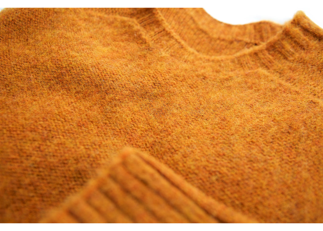 Rust colored long sleeve wool sweater: close-up on crewneck and wrist cuff